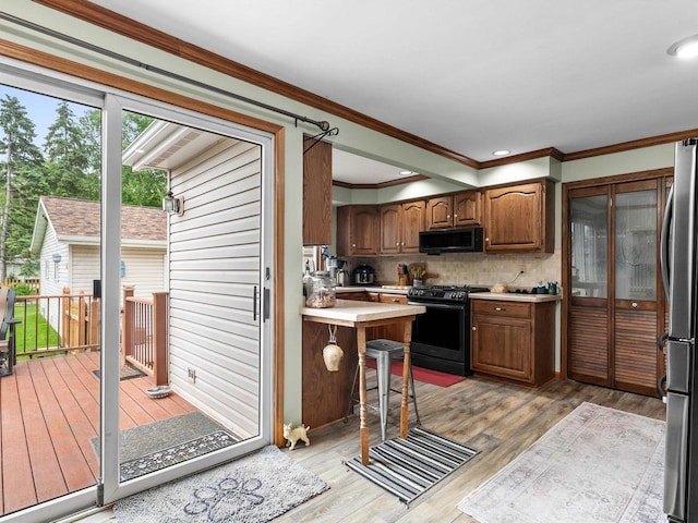 3715 N 17th St, Sheboygan, WI 53083 - kitchen with black appliances, light countertops, backsplash, ornamental molding, and light wood-style floors