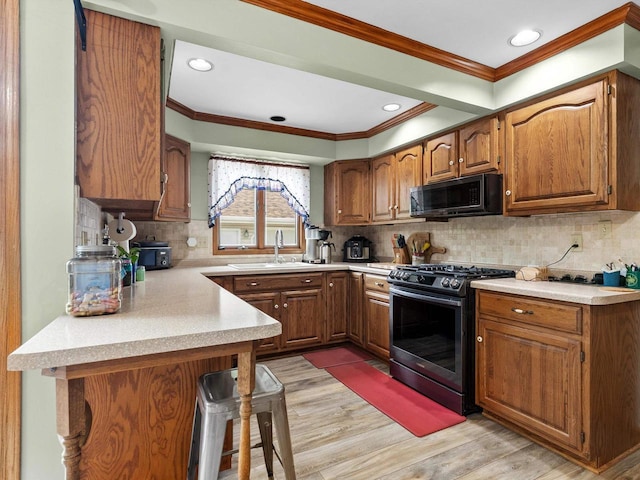 3715 N 17th St, Sheboygan, WI 53083 - kitchen with black microwave, stainless steel gas range, ornamental molding, light wood-type flooring, and brown cabinets