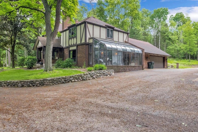 1450 Weber Ct, Hartland, WI 53029 - tudor home with a sunroom, brick siding, and roof with shingles