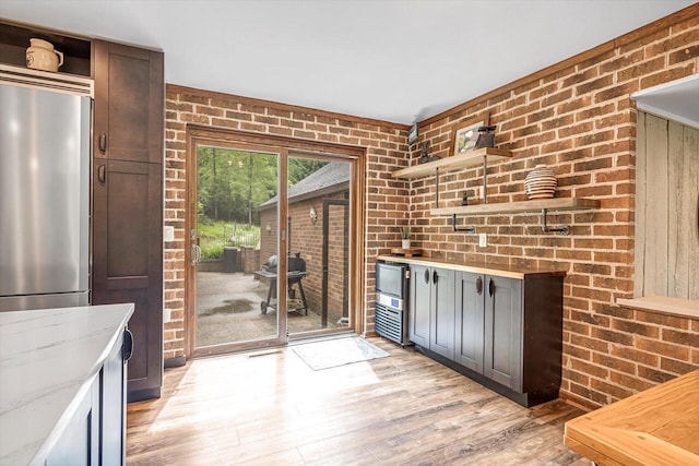 1450 Weber Ct, Hartland, WI 53029 - kitchen featuring open shelves, brick wall, light wood-style flooring, light stone countertops, and fridge