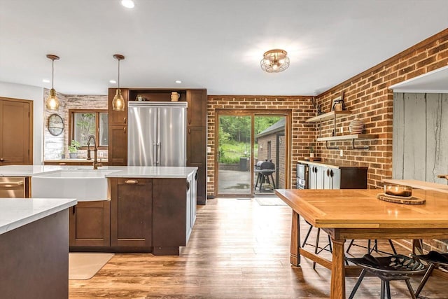 1450 Weber Ct, Hartland, WI 53029 - kitchen with open shelves, appliances with stainless steel finishes, light wood-type flooring, brick wall, and a fireplace
