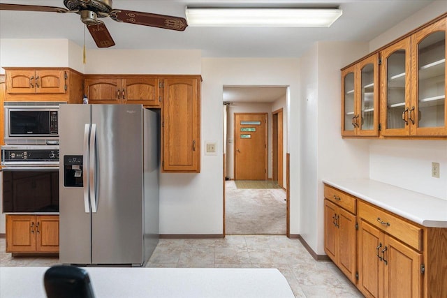 3720 Elm Dr, La Crosse, WI 54601 - kitchen with stainless steel appliances, ceiling fan, glass insert cabinets, light countertops, and brown cabinetry