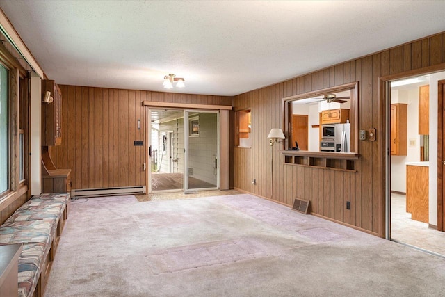 3720 Elm Dr, La Crosse, WI 54601 - unfurnished living room with a baseboard heating unit, carpet flooring, wood walls, a ceiling fan, and a textured ceiling