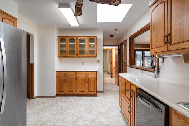 3720 Elm Dr, La Crosse, WI 54601 - kitchen featuring appliances with stainless steel finishes, a skylight, brown cabinetry, light countertops, and glass insert cabinets