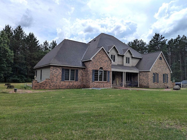 1817 S Duck Creek Dr, Friendship, WI 53934 - view of front facade featuring brick siding, a front lawn, covered porch, and roof with shingles