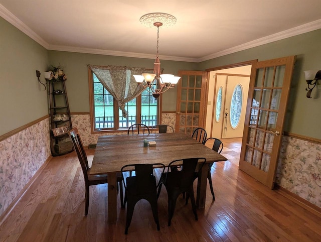 1817 S Duck Creek Dr, Friendship, WI 53934 - dining room with wainscoting, a chandelier, wood finished floors, wallpapered walls, and ornamental molding
