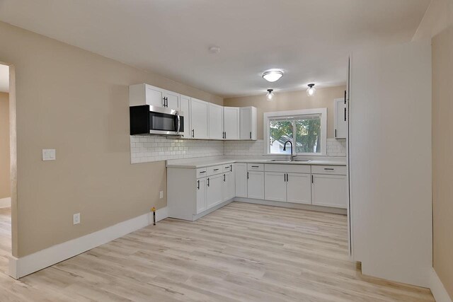 1541 Porter Ave, Beloit, WI 53511 - kitchen featuring stainless steel microwave, tasteful backsplash, light wood finished floors, and white cabinetry