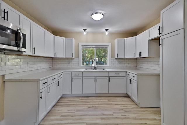 1541 Porter Ave, Beloit, WI 53511 - kitchen with stainless steel microwave, light wood-style floors, backsplash, and white cabinets