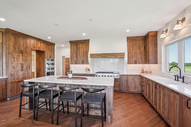 3330 Colton Way, Sun Prairie, WI 53590 - kitchen with brown cabinetry, dark wood-type flooring, recessed lighting, a breakfast bar area, and custom exhaust hood
