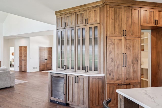 3330 Colton Way, Sun Prairie, WI 53590 - kitchen featuring wine cooler, brown cabinetry, wood finished floors, and glass insert cabinets