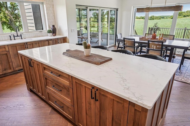 3330 Colton Way, Sun Prairie, WI 53590 - kitchen featuring dark wood finished floors, light stone countertops, brown cabinets, and a center island