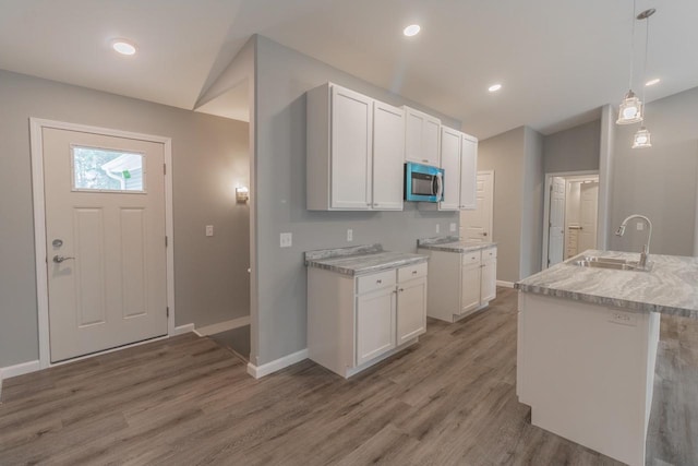 219 Joe St, Stevens Point, WI 54481 - kitchen with stainless steel microwave, light wood-type flooring, white cabinetry, decorative light fixtures, and recessed lighting