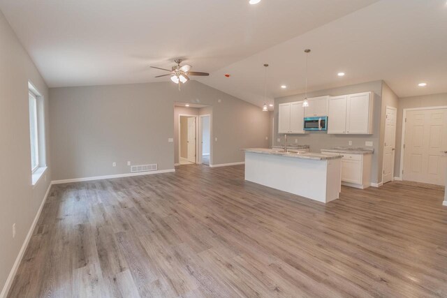 219 Joe St, Stevens Point, WI 54481 - kitchen featuring stainless steel microwave, white cabinetry, open floor plan, a ceiling fan, and light wood-style flooring
