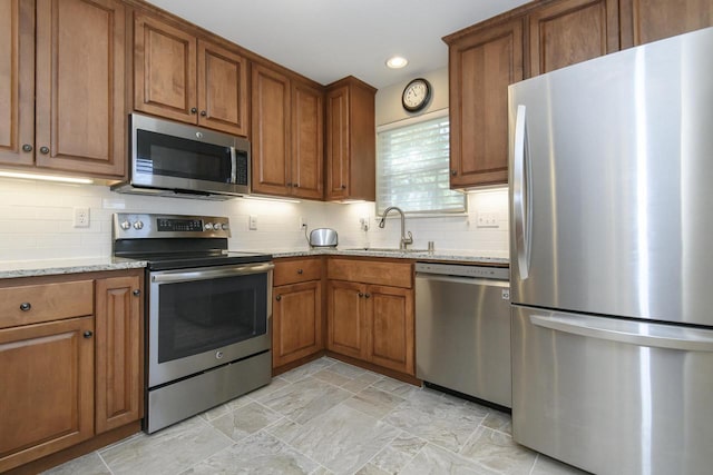 18520 Emerald Cir Unit D, Brookfield, WI 53045 - kitchen with stainless steel appliances, brown cabinets, light stone countertops, decorative backsplash, and recessed lighting