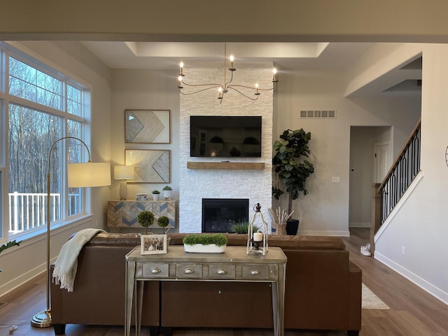 W214N6683 Fairview Dr, Menomonee Falls, WI 53051 - living room with a chandelier, a raised ceiling, wood finished floors, a stone fireplace, and stairway