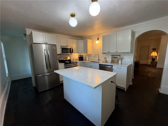 15 S Culver St, Chippewa Falls, WI 54729 - kitchen featuring stainless steel appliances, arched walkways, a center island, white cabinets, and dark wood-type flooring