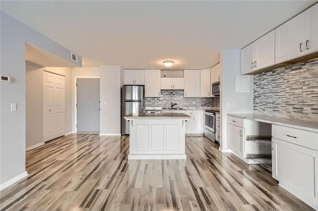 26 10th St Unit 1104, Saint Paul, MN 55102 - kitchen with stainless steel appliances, backsplash, light wood finished floors, white cabinets, and light countertops