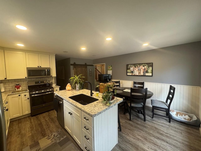 710 Jefferson St, Merrill, WI 54452 - kitchen with appliances with stainless steel finishes, a kitchen island with sink, dark wood-type flooring, tasteful backsplash, and light stone counters