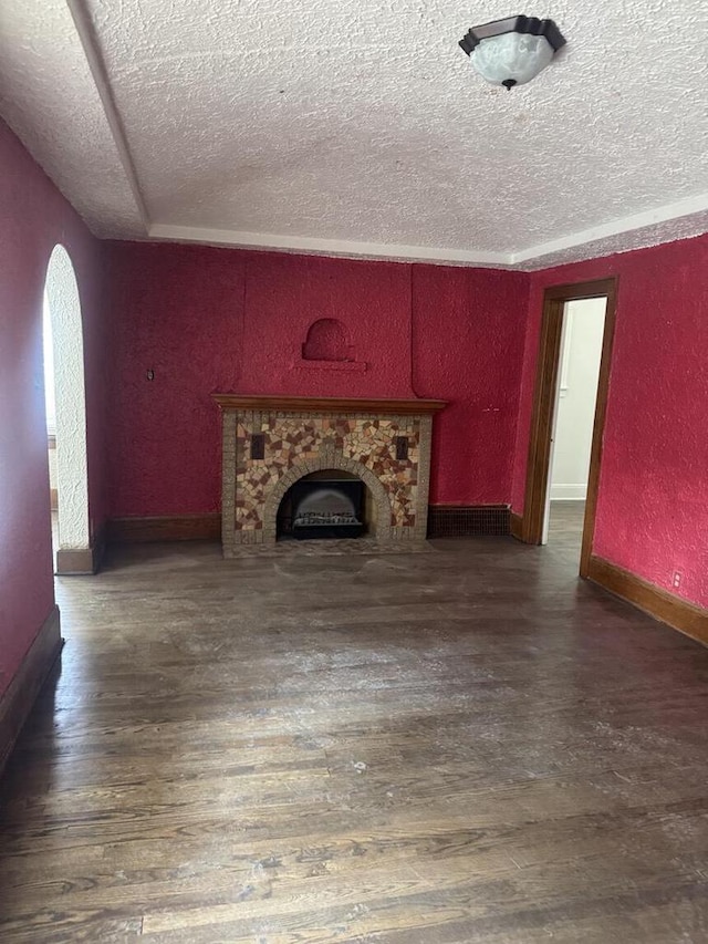 2320 W Hope Ave Unit 2320A, Milwaukee, WI 53209 - unfurnished living room featuring a textured ceiling, a textured wall, wood finished floors, arched walkways, and a fireplace