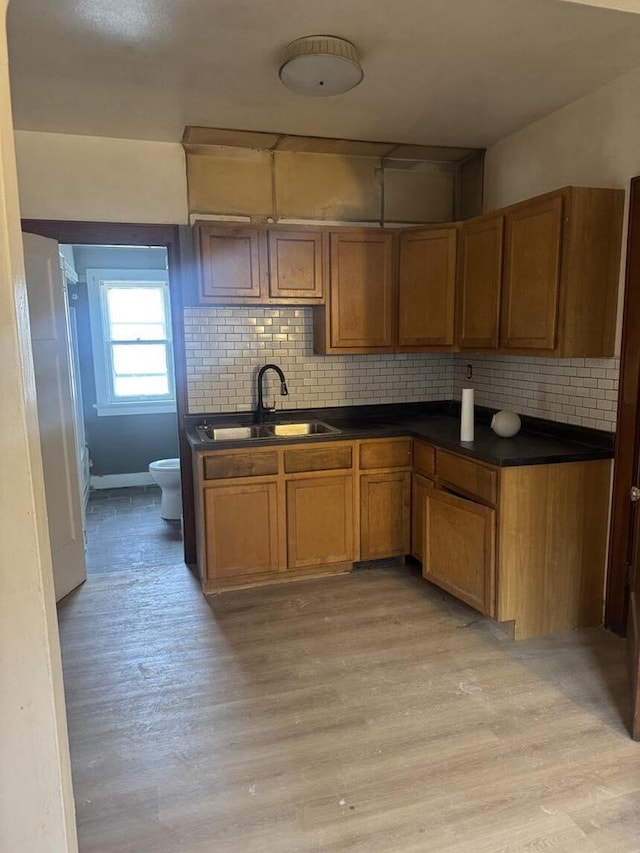 2320 W Hope Ave Unit 2320A, Milwaukee, WI 53209 - kitchen featuring backsplash, brown cabinets, dark countertops, and light wood-style flooring