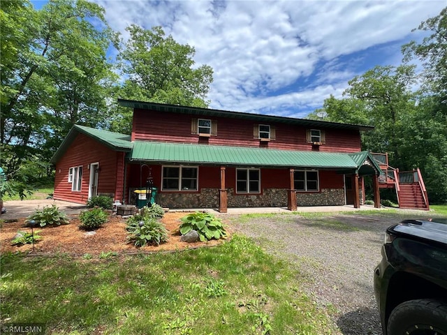 1283 230th Ave, Luck, WI 54853 - rustic home with stone siding, stairs, gravel driveway, a metal roof, and a porch
