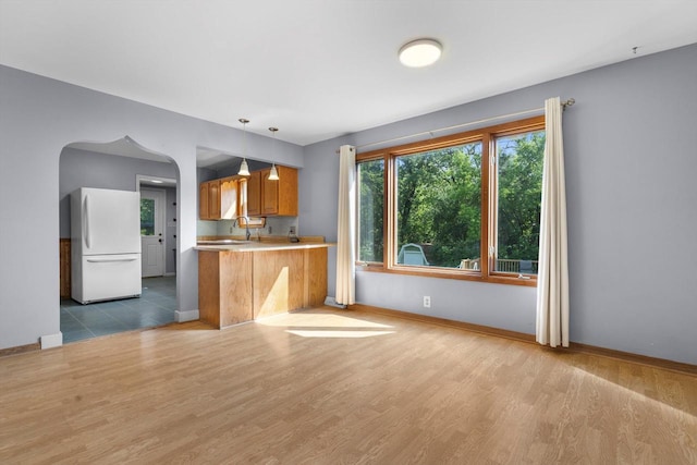 8020 Ridgeway Dr, Burlington, WI 53105 - kitchen featuring freestanding refrigerator, brown cabinets, wood finished floors, light countertops, and decorative light fixtures