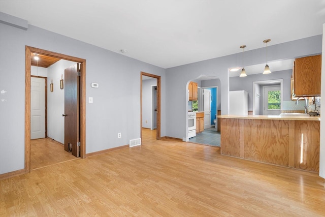 8020 Ridgeway Dr, Burlington, WI 53105 - kitchen with light wood-style floors, arched walkways, light countertops, white appliances, and a peninsula