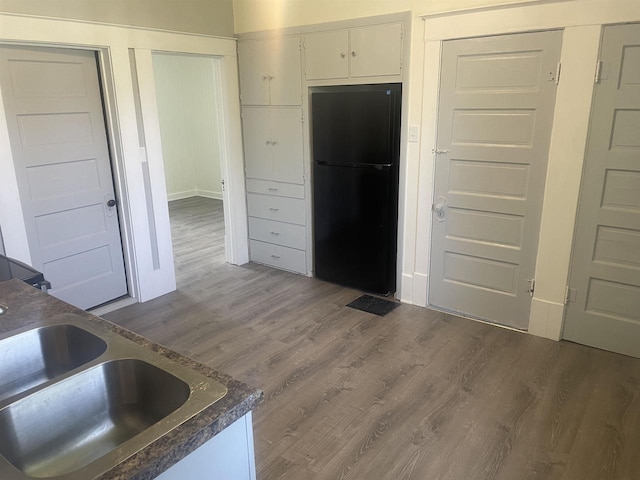 510 S Vine Ave, Marshfield, WI 54449 - kitchen featuring freestanding refrigerator, wood finished floors, dark countertops, and white cabinets