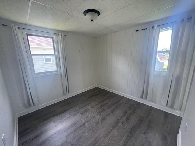 510 S Vine Ave, Marshfield, WI 54449 - unfurnished room featuring dark wood-style flooring, a paneled ceiling, and wooden walls
