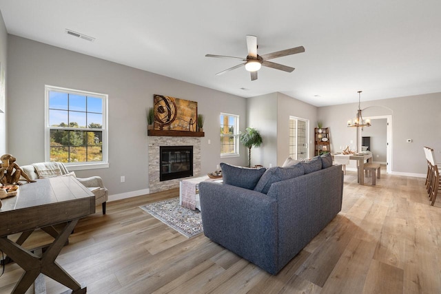 1883 Woodland Way, Slinger, WI 53086 - living area with a chandelier, light wood-style floors, a stone fireplace, and a ceiling fan
