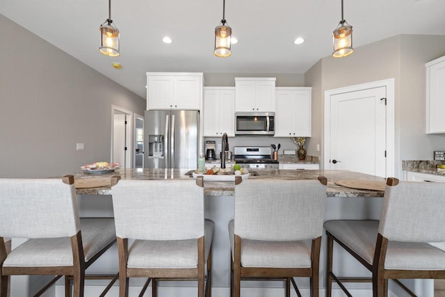 1883 Woodland Way, Slinger, WI 53086 - kitchen with appliances with stainless steel finishes, pendant lighting, white cabinetry, light stone countertops, and a kitchen breakfast bar