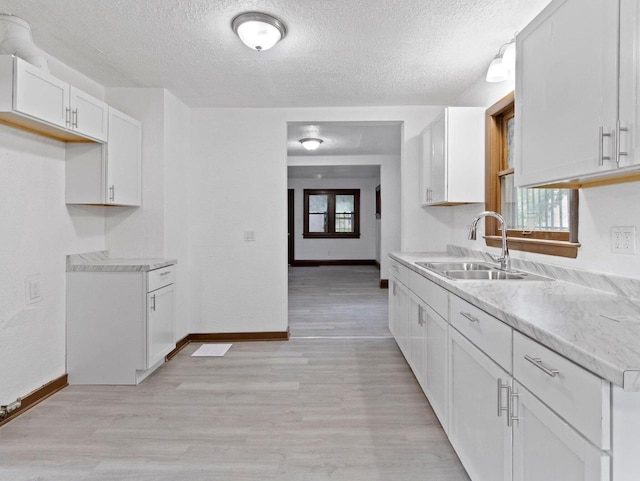 5751 N 38th St, Milwaukee, WI 53209 - kitchen with a textured ceiling, light wood-style flooring, light countertops, and white cabinetry