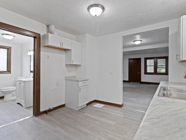 5751 N 38th St, Milwaukee, WI 53209 - kitchen with light wood-style flooring, white cabinets, light countertops, and a textured ceiling