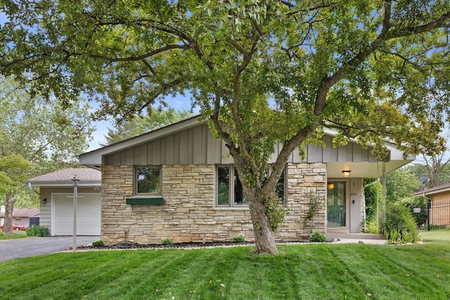 6196 N River Trail Dr, Milwaukee, WI 53225 - view of front of property with stone siding, an attached garage, board and batten siding, driveway, and a front lawn