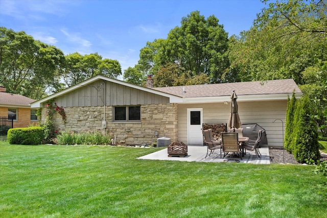 6196 N River Trail Dr, Milwaukee, WI 53225 - rear view of house featuring a patio area, an outdoor fire pit, stone siding, a yard, and a shingled roof