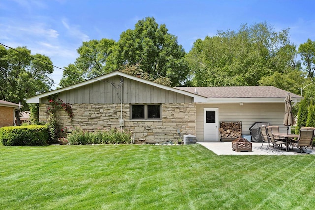 6196 N River Trail Dr, Milwaukee, WI 53225 - rear view of house featuring stone siding, a fire pit, a lawn, a patio area, and board and batten siding