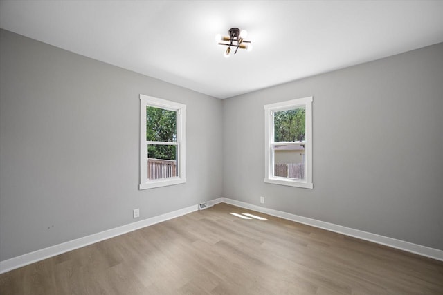 7705 241st Ave, Salem, WI 53168 - empty room with healthy amount of natural light, wood finished floors, and a chandelier