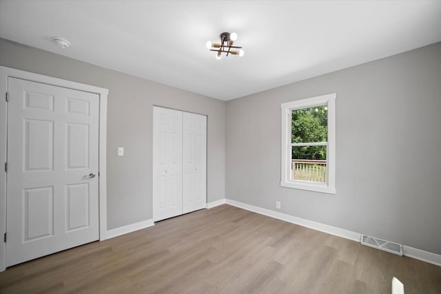 7705 241st Ave, Salem, WI 53168 - unfurnished bedroom with wood finished floors, a chandelier, and a closet
