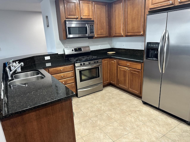 333 W Mifflin St Unit 1156, Madison, WI 53703 - kitchen with appliances with stainless steel finishes, dark stone counters, a peninsula, light tile patterned floors, and brown cabinetry