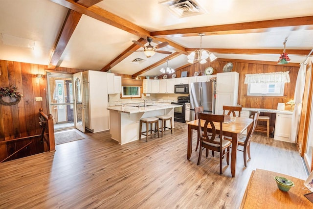 2278 S Riverside Dr, Beloit, WI 53511 - dining space featuring wooden walls, light wood-style flooring, healthy amount of natural light, a ceiling fan, and a chandelier