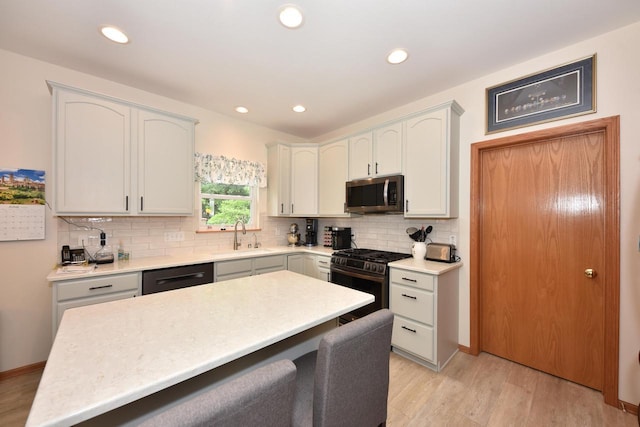 847 Chisholm Ln, Port Washington, WI 53074 - kitchen featuring appliances with stainless steel finishes, a breakfast bar, decorative backsplash, light countertops, and light wood-style floors