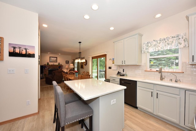 847 Chisholm Ln, Port Washington, WI 53074 - kitchen featuring black dishwasher, light wood-type flooring, a kitchen island, tasteful backsplash, and a kitchen breakfast bar