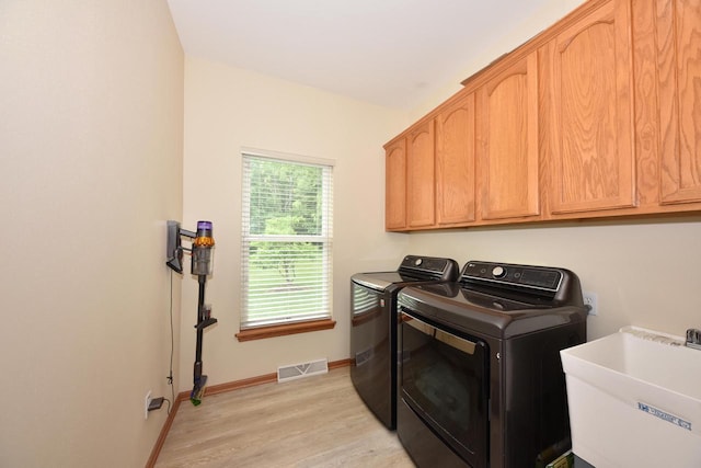 847 Chisholm Ln, Port Washington, WI 53074 - laundry area featuring washer and clothes dryer, cabinet space, and light wood-type flooring