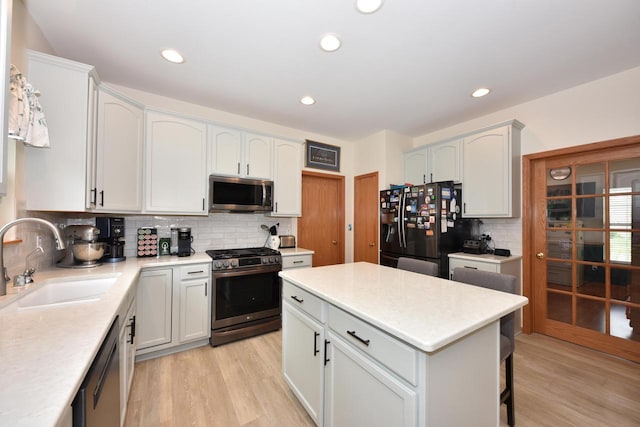 847 Chisholm Ln, Port Washington, WI 53074 - kitchen with stainless steel appliances, backsplash, light wood-style floors, light countertops, and a center island