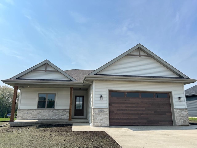 1310 Spahn Dr, Waunakee, WI 53597 - view of front of house with stone siding, driveway, an attached garage, and a shingled roof
