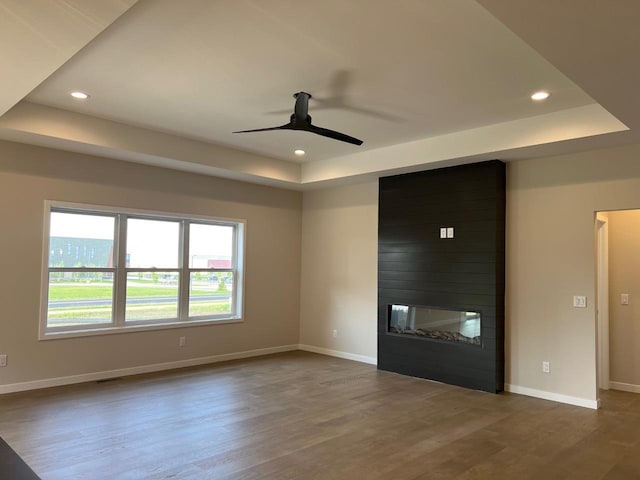 1310 Spahn Dr, Waunakee, WI 53597 - unfurnished living room with a raised ceiling, a ceiling fan, wood finished floors, recessed lighting, and a large fireplace