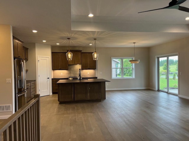 1310 Spahn Dr, Waunakee, WI 53597 - kitchen with stainless steel fridge with ice dispenser, wood finished floors, recessed lighting, dark countertops, and decorative backsplash