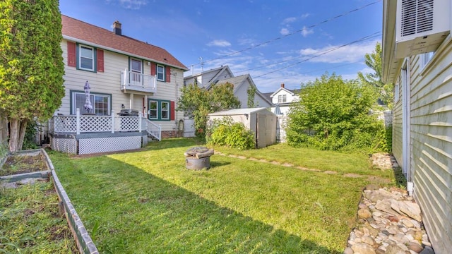 1345 Annie Ct, Sheboygan, WI 53083 - fenced backyard with a storage unit, a fire pit, a vegetable garden, and a wooden deck