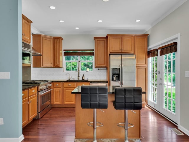 N8986 Swift Lake Dr, East Troy, WI 53120 - kitchen featuring stainless steel appliances, decorative backsplash, a kitchen island, dark wood-type flooring, and a kitchen bar
