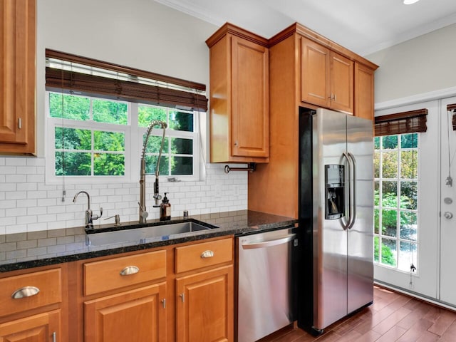 N8986 Swift Lake Dr, East Troy, WI 53120 - kitchen featuring appliances with stainless steel finishes, tasteful backsplash, brown cabinets, dark stone counters, and ornamental molding